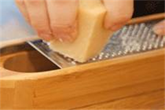 Cheese being grated over a cheese grater 